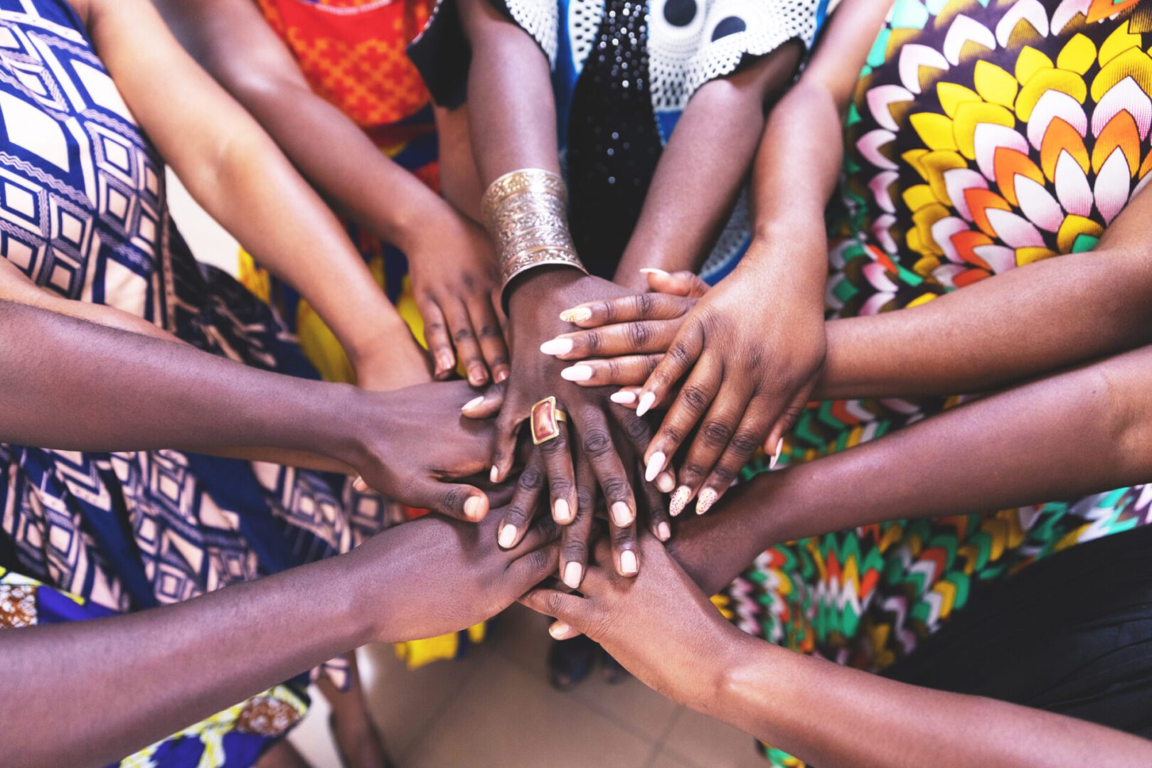 Hands united in colorful patterned clothing.