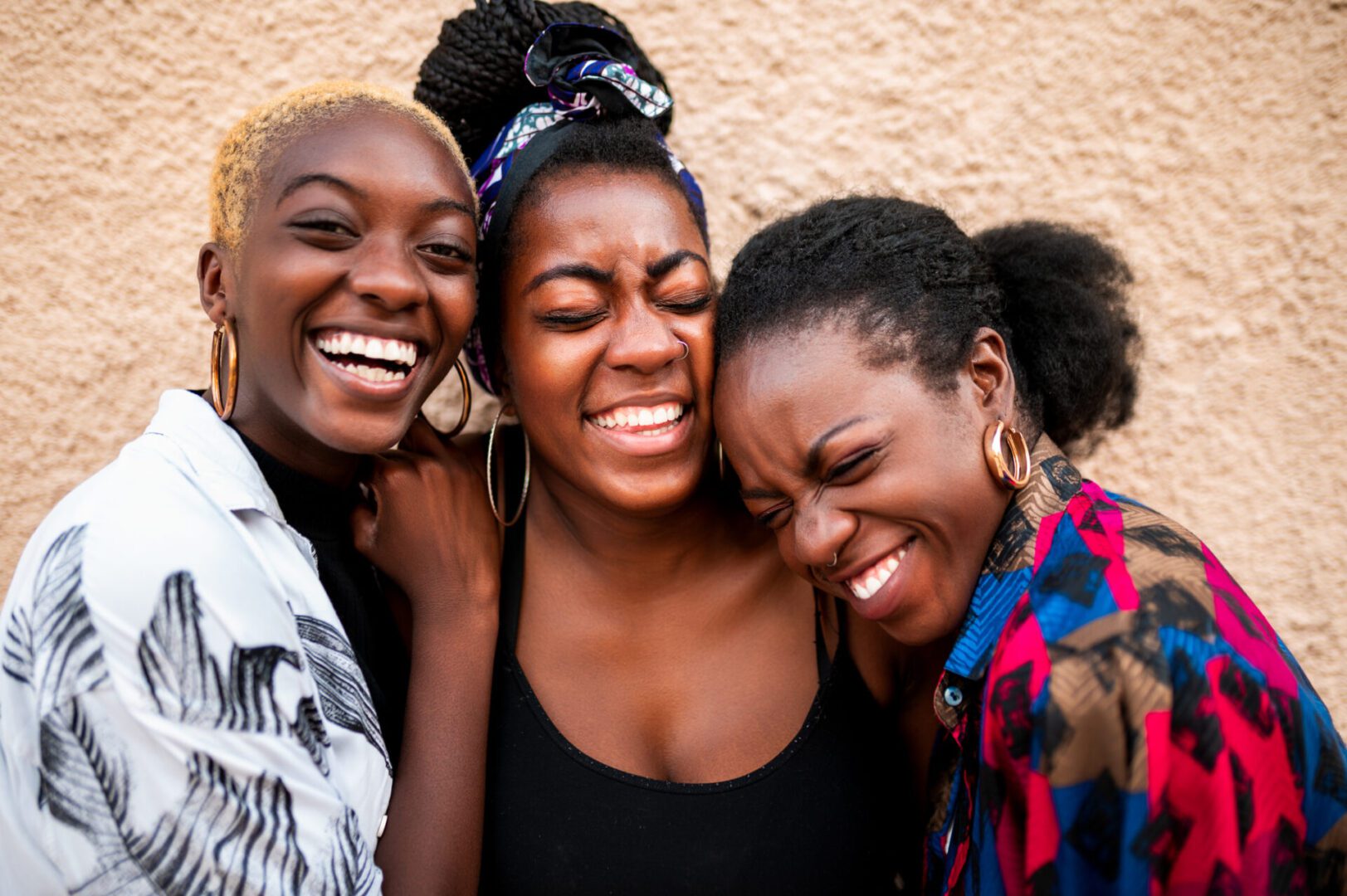 Three friends laughing together, close-up portrait.