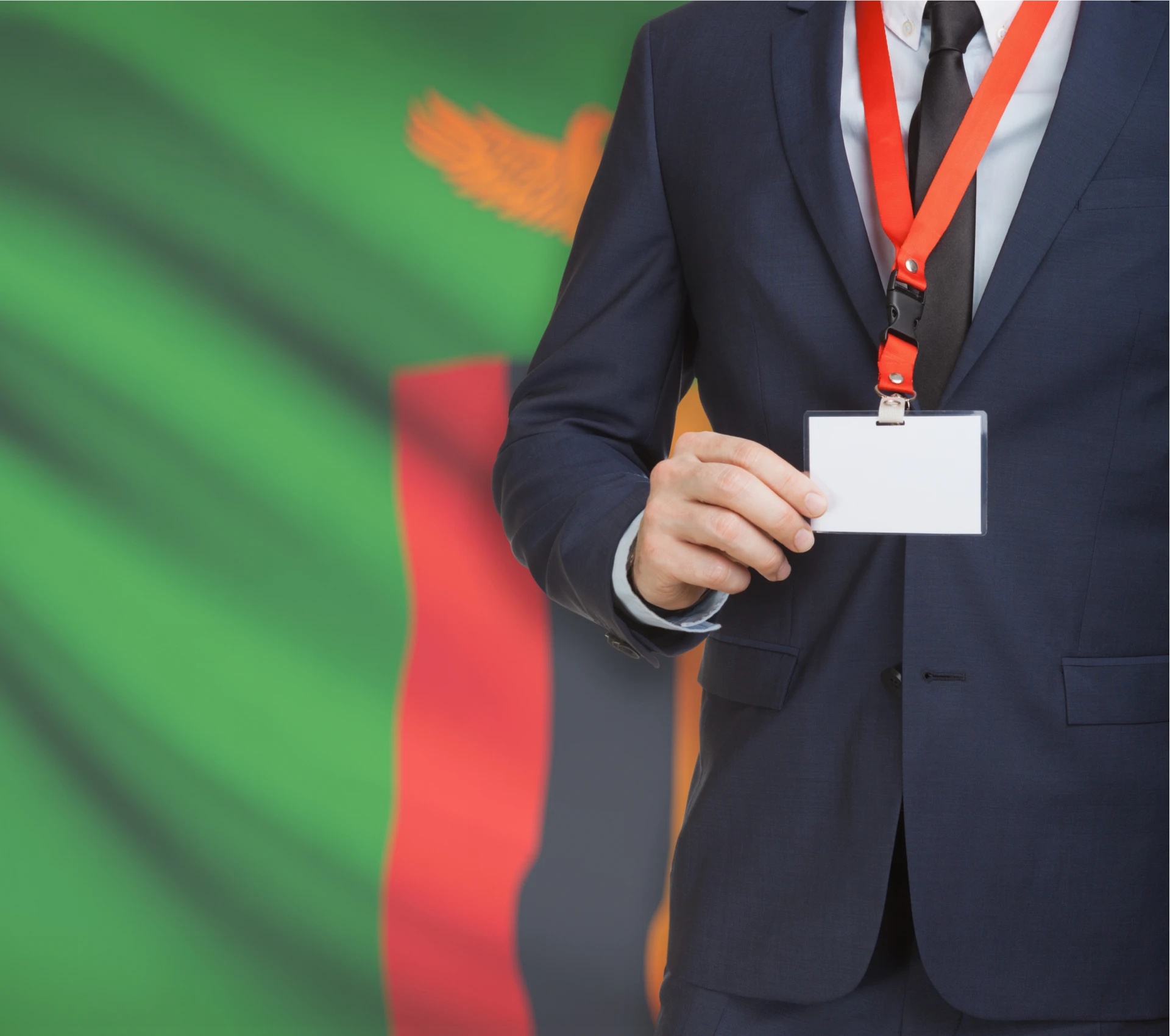 Man holding ID badge, Zambia flag background.