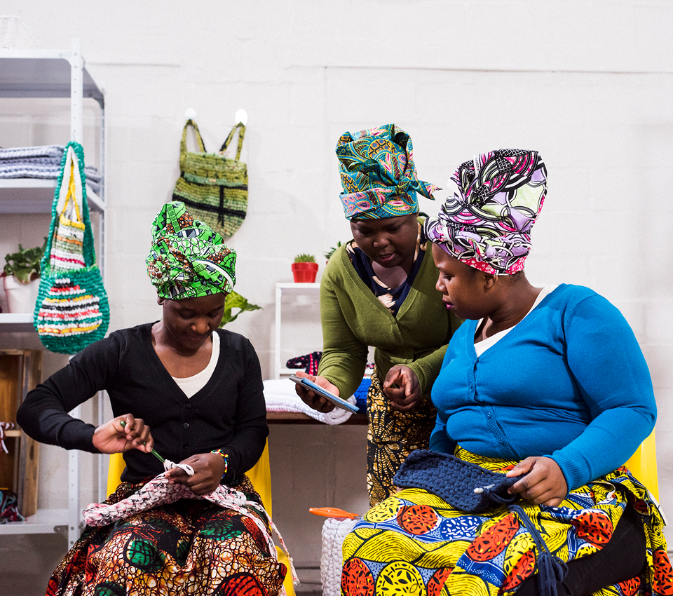 Women sewing with colorful fabrics and headwraps.