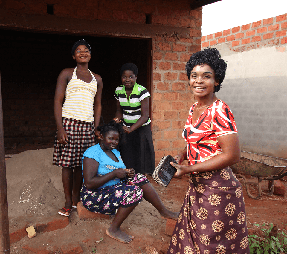 Four women smiling outside a brick building.